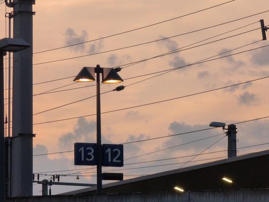 A train station at dusk. Signs are visible that indicate platforms 13 and 13.