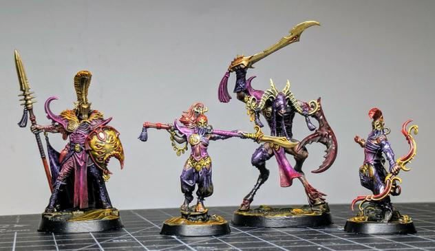 Four painted miniatures wielding fantastical weapons. One of them is a beastman with horns.