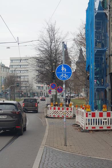 Straße mit Autoverkehr, enger Fußweg mit Verkehrszeichen (240) - StVO Gemeinsamer Fuß- und Radweg und einer Baustelle.