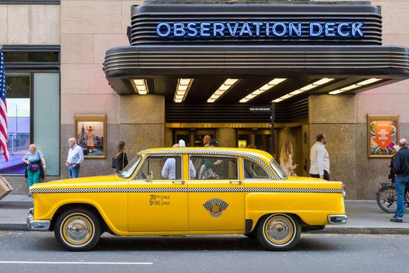 Ein altes Taxi in der typischen gelben Farbe steht vor dem Eingang zum Observation Deck des Rockefeller Centers.