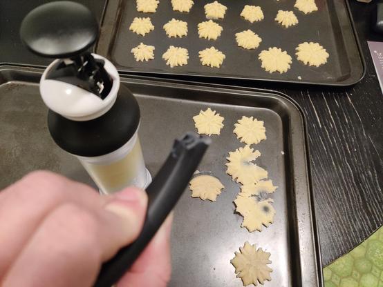 POV: you just broke your wife's new cookie press. A broken, black, plastic handle is in your left hand. Dough with your knuckle prints is on a cookie sheet in the background. It's not funny.