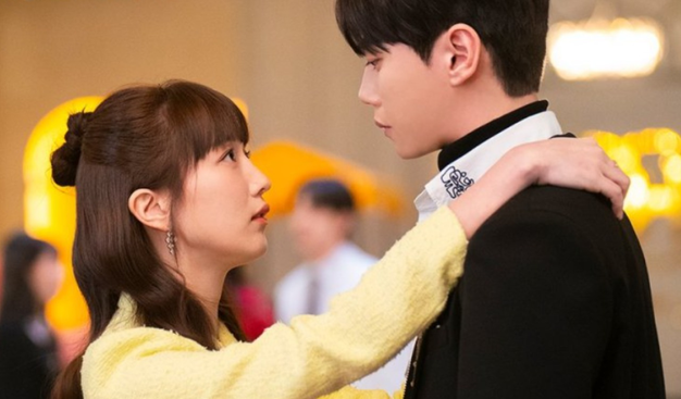 Pyo Ye Jin in a yellow dress facing Lee Jun Young in a suit with her arms around his neck from the 2024 South Korean drama "Dreaming of a Freaking Fairytale."