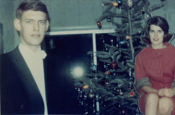 A photo included in a family christmas card, probably from the 1980s.  A young blonde overexposed man in a suit coat and dress hshirt stands at left, in front of a large uncovered window that's reflecting the flash from the camera, and a decorated christmas tree adorned with tinsel and lights that, given the room lighting and the flash, can't be definitely said to be lit or not.  Superimposed in front of the tree is a pasted-in image of a young woman in a red dress with very large buttons.  She was originally photographed in a seated position and further from the camera than the young man, so she appears peculiarly smaller, as if in the background.  Her position has been elevated to put her higher up in the frame at perhaps the height she would be if standing, creating the impression that she's floating in midair from a seated position.  Surrounding her is the fringe of background from whatever scene she was originally photographed in, with a hard border where she's superimposed on the second photograph.

This is a single re-shot print, not a superimposed negative.