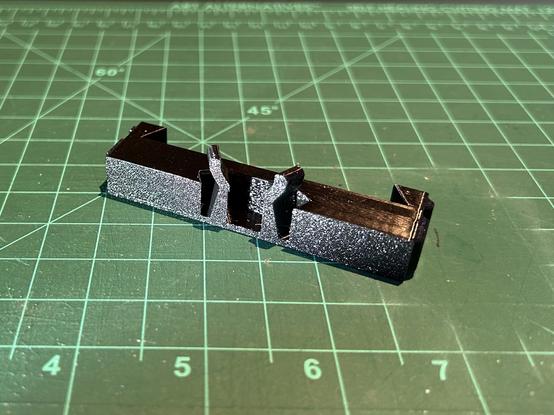 A black printed adapter piece has a trapezoidal slot for a tube inlet.  The two diagonal sides of the slot are flexible.  On the top of each is a small tab that you can use to push the flexible parts open.