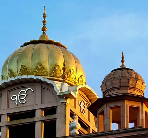 A golden dome and a smaller pink granite dome on the top of a Glasgow Gardwara.