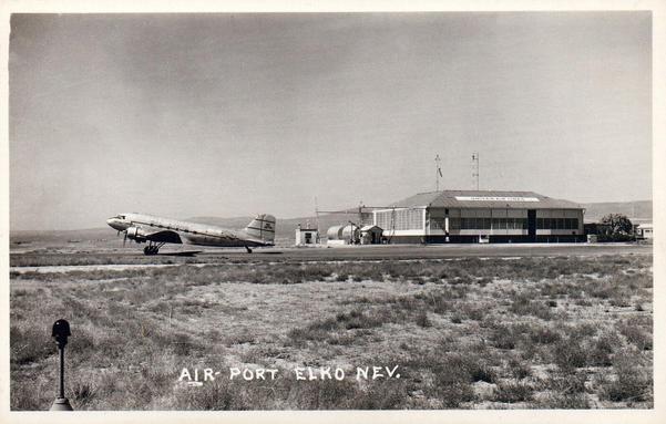 A lone prop plane speeds away down a taxiway. In the back ground is an old United Air Lines hanger.