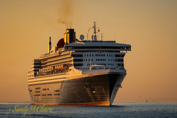 Black hulled ocean liner approaching the camera at dawn.