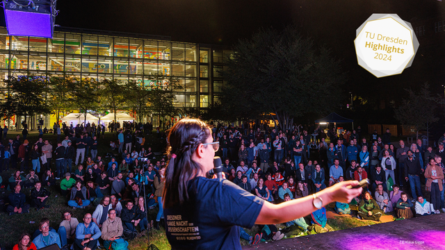 Foto von der Open-Air-Bühne, auf der eine Frau steht, die in ein Mikro spricht. Es ist Nacht. Im Hintergrund sitzen viele Menschen. Zudem ist das erleuchtete Hörsaalzentrum zu sehen.
