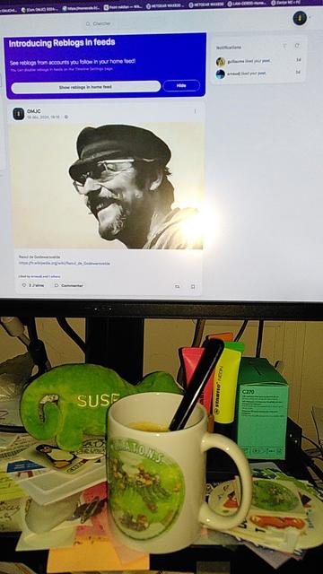 Une tasse de café, illustrée par David Revoy, posée devant un écran.