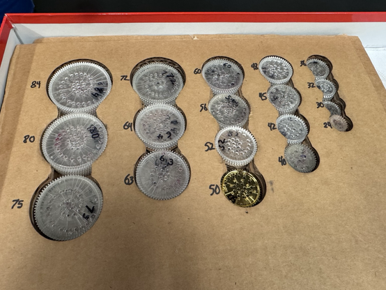 A cardboard holder with labeled holes for spirograph rings.