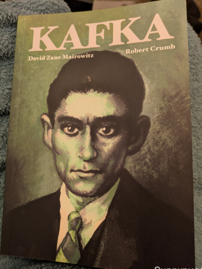 Buchcover von einer Art Comic zu Kafka, illustriert von Robert Crumb. Zu sehen ist ein Porträt von Kafka.