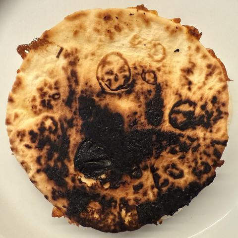 Shamefully burnt tortilla. Near the top-center is what is CLEARLY the face of Skeletor from He-Man.