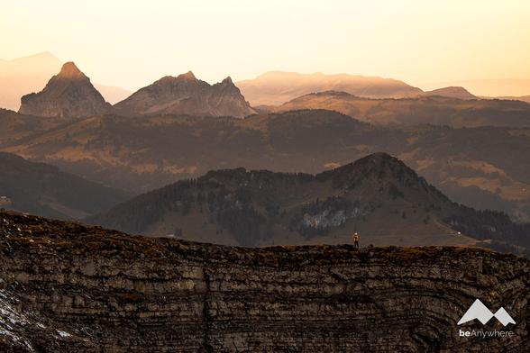 The woman taking the photo is standing on a rock face. Behind her is the Mythen region.