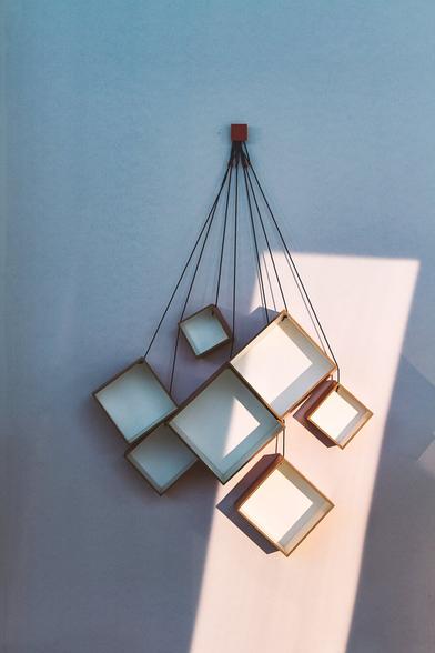 photo of some modern looking decoration pieces handing on a wall illuminated by a single bold ray of sun.