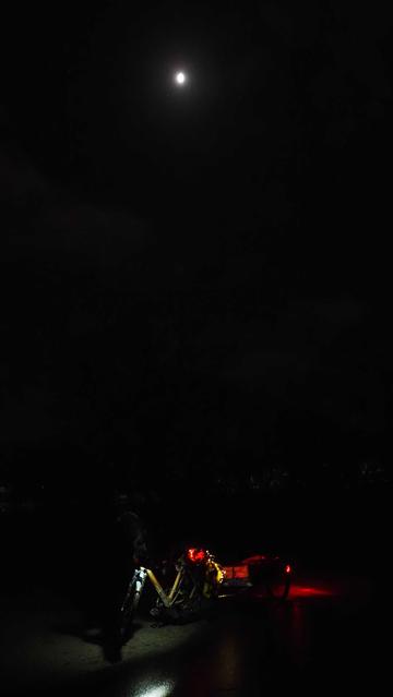 Kleiner Mond über einem beleuchteten Fahrrad