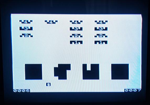 A photo of Flicker Free Space Intruders running on the ZX80 clone, displayed on a Sony Trinitron TV. Image shows rows of space invaders and shields with your little space ship at the bottom.