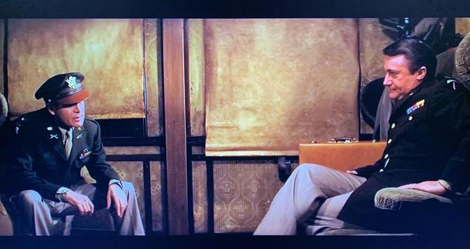 Patrick McGoohan and Robert Vaughn sit on a train facing each other, both in uniform, looking extremely serious about their conversation. So much awesomeness in one photo.