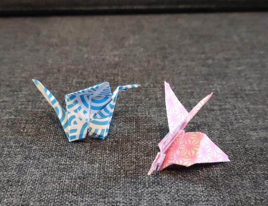 A blue and white origami crane and a pink and white origami crane.