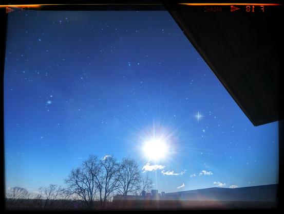 Same images before with the sun rising Into the Blue Skies with the tree in the foreground and the building, but now many many more stars are visible