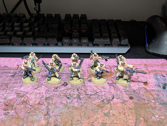 10 old 1995 Delaque gang miniatures for the game Necromunda. They have long beige coats and various melee and ranged weapons.