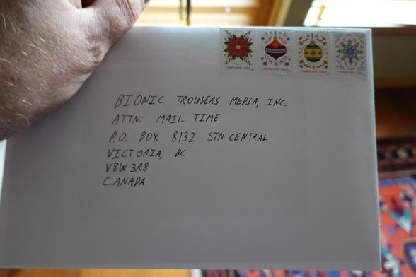 An envelope addressed to the address for LoadingReadyRun's Mail Time. The poster's hand is strategically holding the envelope at the upper left corner in order to obscure the return address.
