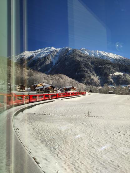 Foto. Ein roter Zug in Berglandschaft.