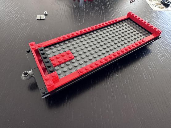 The same carriage, but now the under structure is hidden. The carriage is rectangular, with a light grey base, red edging, and black highlights.