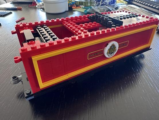 The partially assembled coal cart, featuring red and yellow colors with a Hogwarts crest on the side. The top “coal” structure is only starting to take shape.