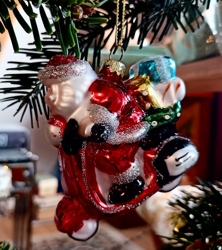 Ein bunter Christbaumschmuck: ein Weihnachtsmann im roten Anzug auf einem Moped,  auf dem Rücksitz ein Berg Geschenke