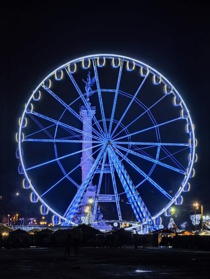 Grande roue place des Quinconces, de nuit. La colonne des Girondins est visible derrière. Au pied de la grande roue on devine le marché de Noël.