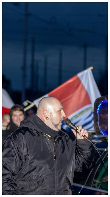 Seitlich auf dem Foto zu sehen ist ein dickerer Mann Florian Grabowski mit Glatze am Mikrofon zu sehen.