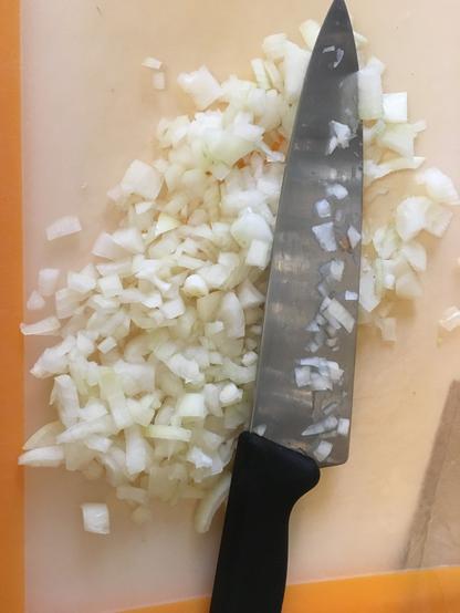 Chopped onions on a cutting board with a chef’s knife.