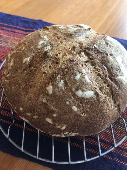 A round loaf of homemade sourdough bread sitting on a cooling rack