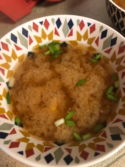 bowl of miso tofu soup with green onions floating on top