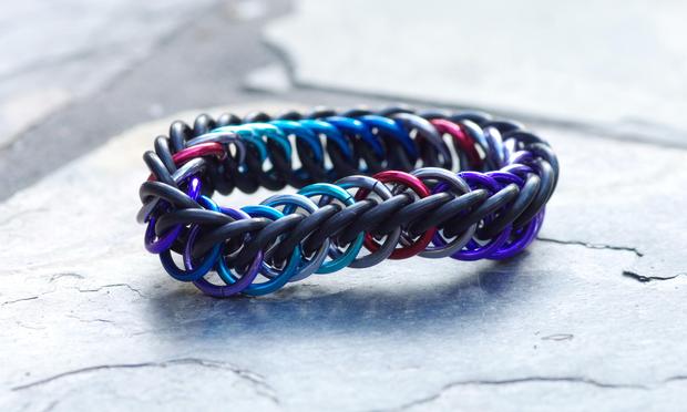 A very small chainmail bracelet in black rubber and shades of blue, purple, red and silver.