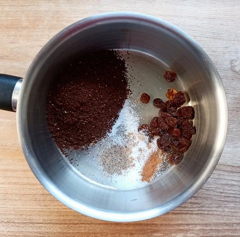 In einem kleinen Topf Kaffeepulver, Rosinen, Zucker, Kardamom und Zimt