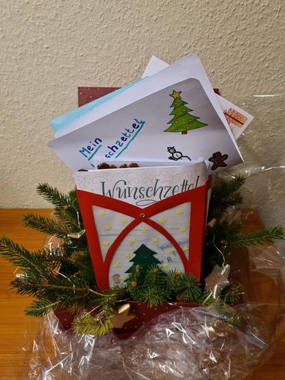 Gefüllte weihnachtliche Geschenktüte, aus der ein handgeschriebener Wunschzettel herausragt.