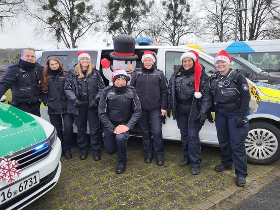 Beschäftigte der Finanzkontrolle Schwarzarbeit vor einem geschmückten Zoll Einsatzwagen bei der Hildesheimer Lichterfahrt.