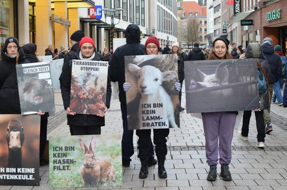 vier aktivis halten vegane schilder in der ludgeristraße "ich bin kein lamm braten" steht auf einem schild mit einem lamm drauf