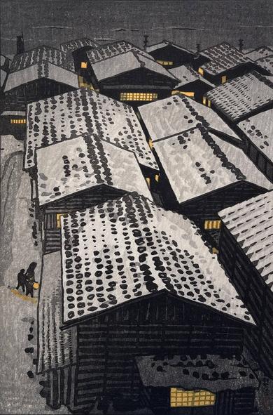 Winter night gathers around a village by the sea. Snow covers the ground and the tile rooftops of the houses; warm lights glow in the windows. A figure carrying a lamp accompanies a smaller figure through the snow, approaching one of the houses. Beyond, the wintry Sea of Japan is dark, grey, and cold.