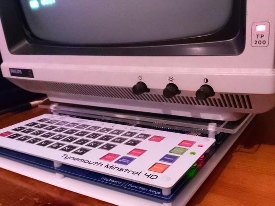 Photo showing Philips monitor on top of the computer but supported by an acrylic platform that extends a little further left+right and further back.