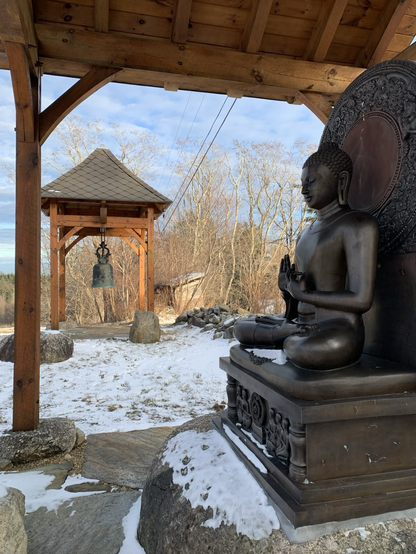 A Buddha Rupa besides a bell tower.
