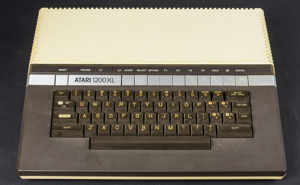 Ein beiger Tastaturcomputer mit fast quadratischer Grundfläche. Die abgeschrägte Front ist wie die Tastatur darin in Braun gehalten, mit einem silbernen Streifen Funktionstasten darüber. Bild Wikipedia.