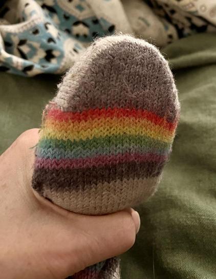 The end of the darning egg that’s shaped kind of like a foot is inside a sock heel, with the sock pulled around it to make a flat, smooth area that could be darned. My pinky beige hand is holding the sock around the handle so that it doesn’t flop around.