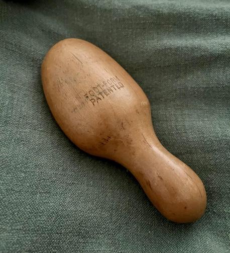 A wooden blobby thing on a green piece of fabric. One end is a handle, while the other is shaped more or less like the toe end of a shoe.

It is stamped with the words “Foot-form patented” but the patent has probably expired by now.