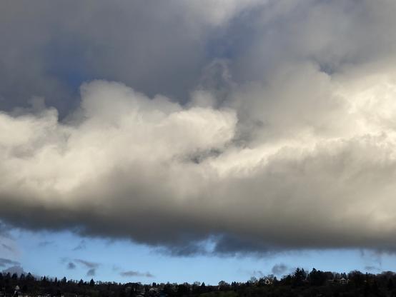 Dramatisch beleuchtete Wolken über einer Landschaft.