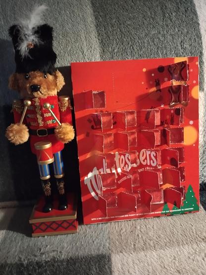 Nutcracker bear standing next to a maltesers advent calendar.