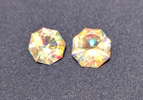 2 pieces of faceted glass in a barion design cut  from an X-cube. X-cubes are 4 pieces of optically  clear glass glued together with a Dicrolic film between them. They are or were used in projectors. Normally when white light enters ones side green goes out the back and red or blue go out the sides. In these since the colors are mixing I am getting teal, yellow white and red, blue, green colors reflected back.

Like a poor mans rutile.
