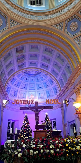 Merry Christmas to you and your loved ones. Chapel from Our Lady of Angels Church, Pondicherry. 
In the photograph, Jesus on Cross while two chubby Angels holding the Joyeux noel sign above the cross. 
Next to Jesus are two decked Christmas trees.
And rows of bouquets decorating the Chapel.