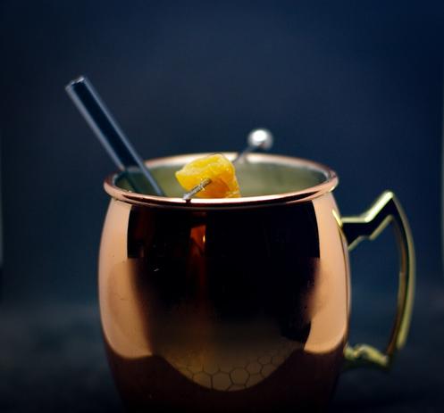 The mocktail, the third one, in a copper mug. The only visible part is the glass straw and the ginger cube.